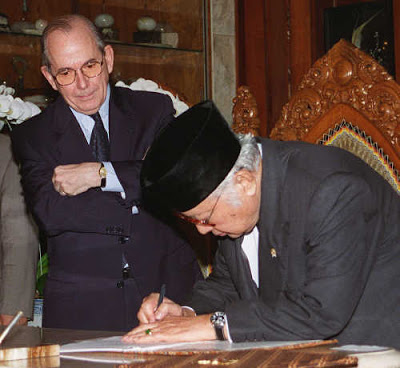 The Iconic Image of IMF Power: IMF Managing Director Michel Camdessus looking on as Indonesia's President Soeharto signs a second bailout agreement, January 1998